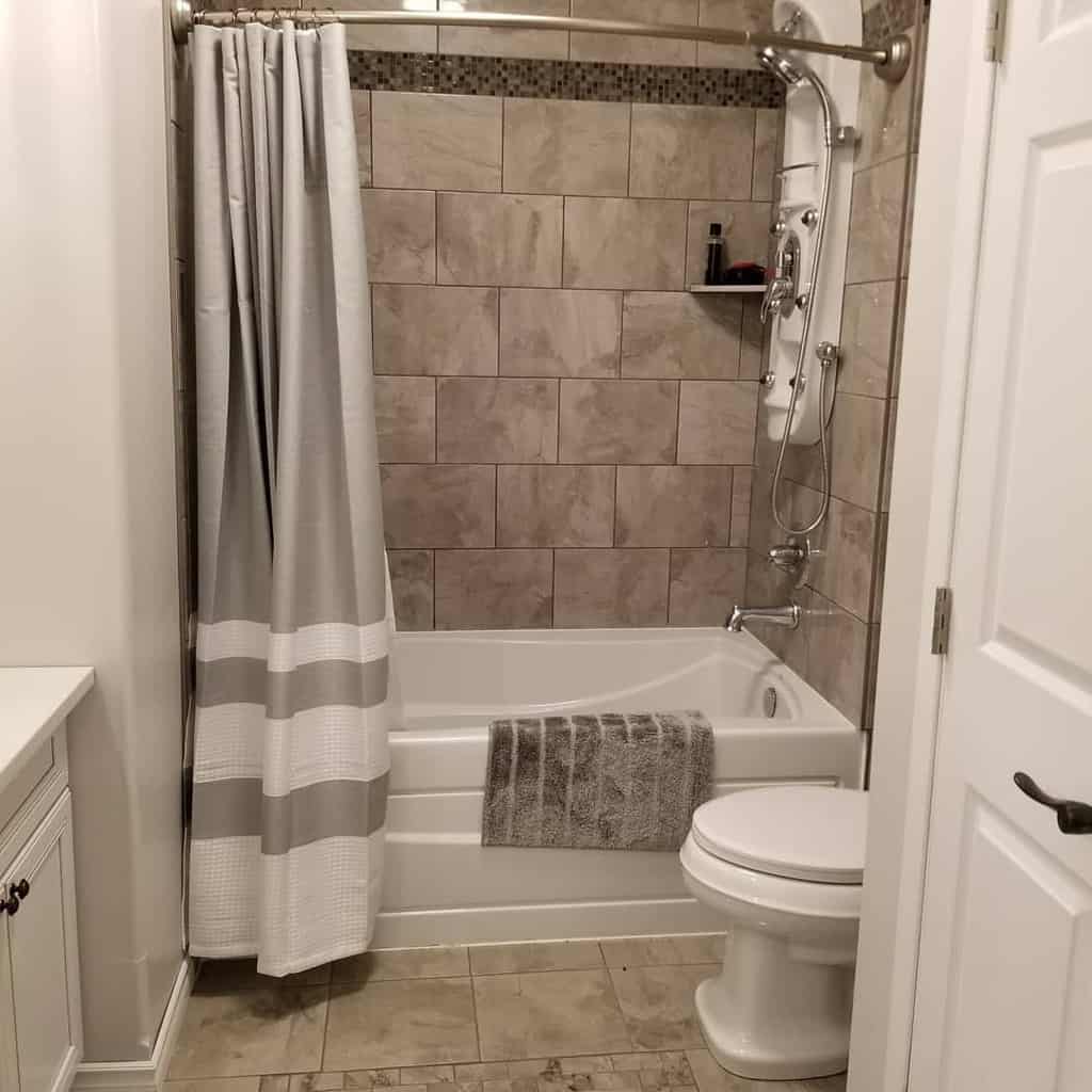 Modern bathroom with grey tiled shower, white bathtub, and matching grey shower curtain.