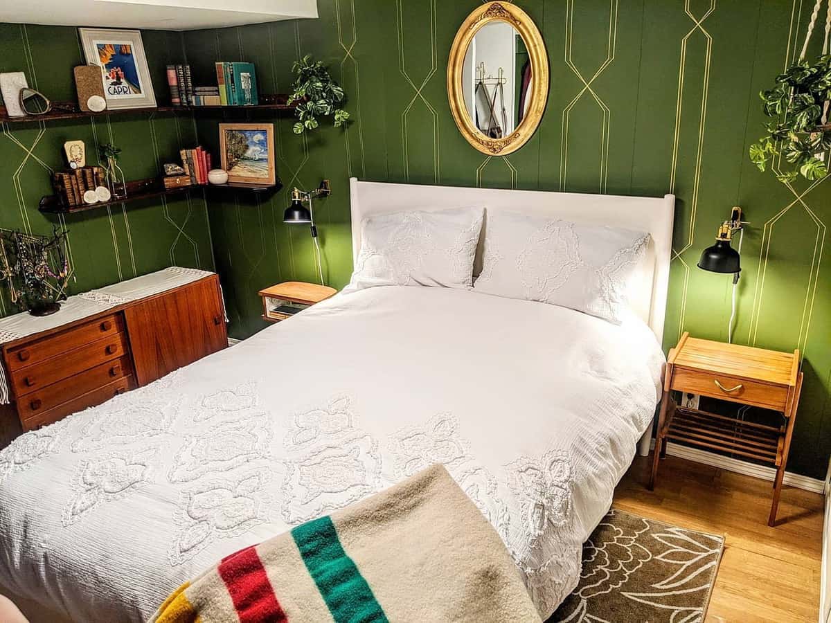 Cozy bedroom with green accent walls, wooden furniture, and decorative shelving.