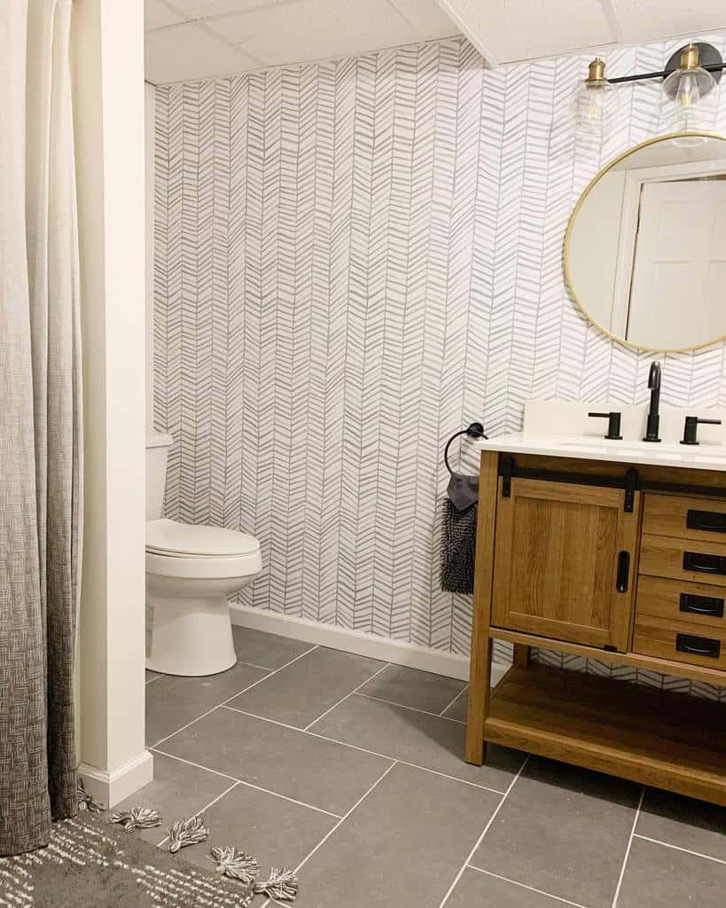 Homely bathroom with patterned wall, wooden vanity, and grey tiled floor.