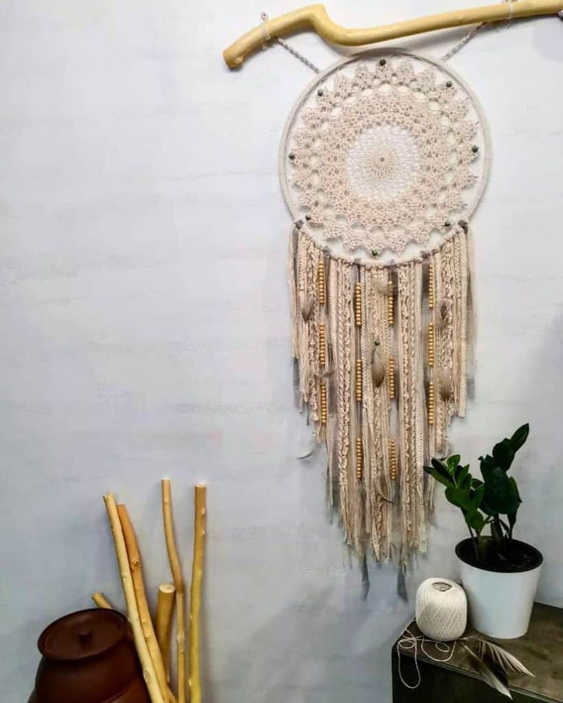 Boho dreamcatcher wall decor with wooden accents and potted plant nearby.