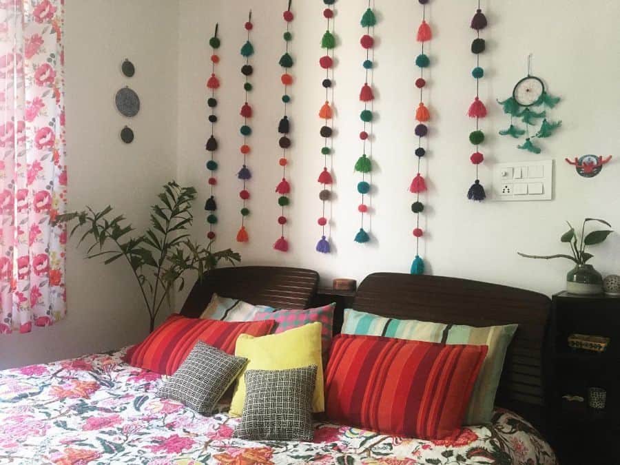 Colorful pom-pom wall art above bed with vibrant pillows and floral bedding.