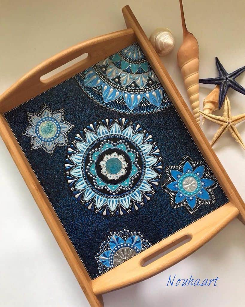 Wooden tray with blue mandala art design and decorative seashells and starfish.