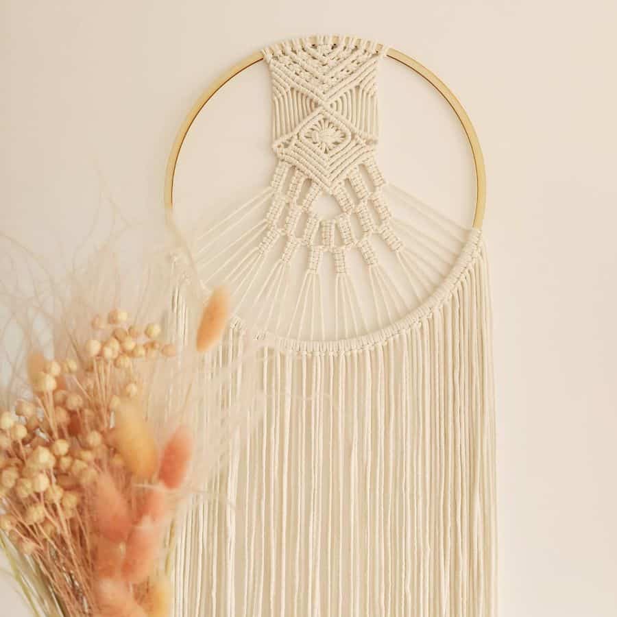 Bohemian macrame wall hanging with intricate patterns on a gold circular frame.