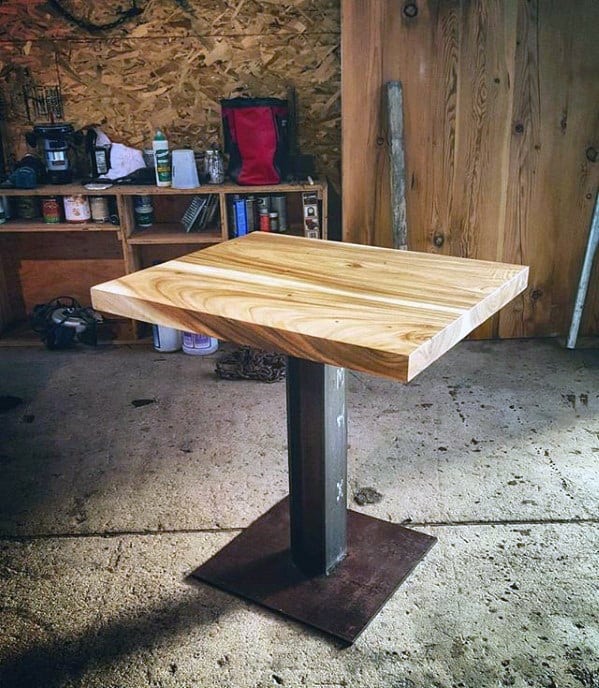A small wooden table with a sturdy metal base in a workshop setting