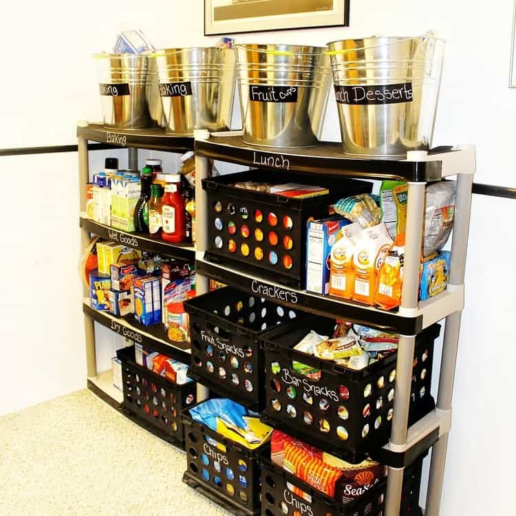 Organized pantry shelves with labeled bins and metal buckets storing snacks and dry goods.