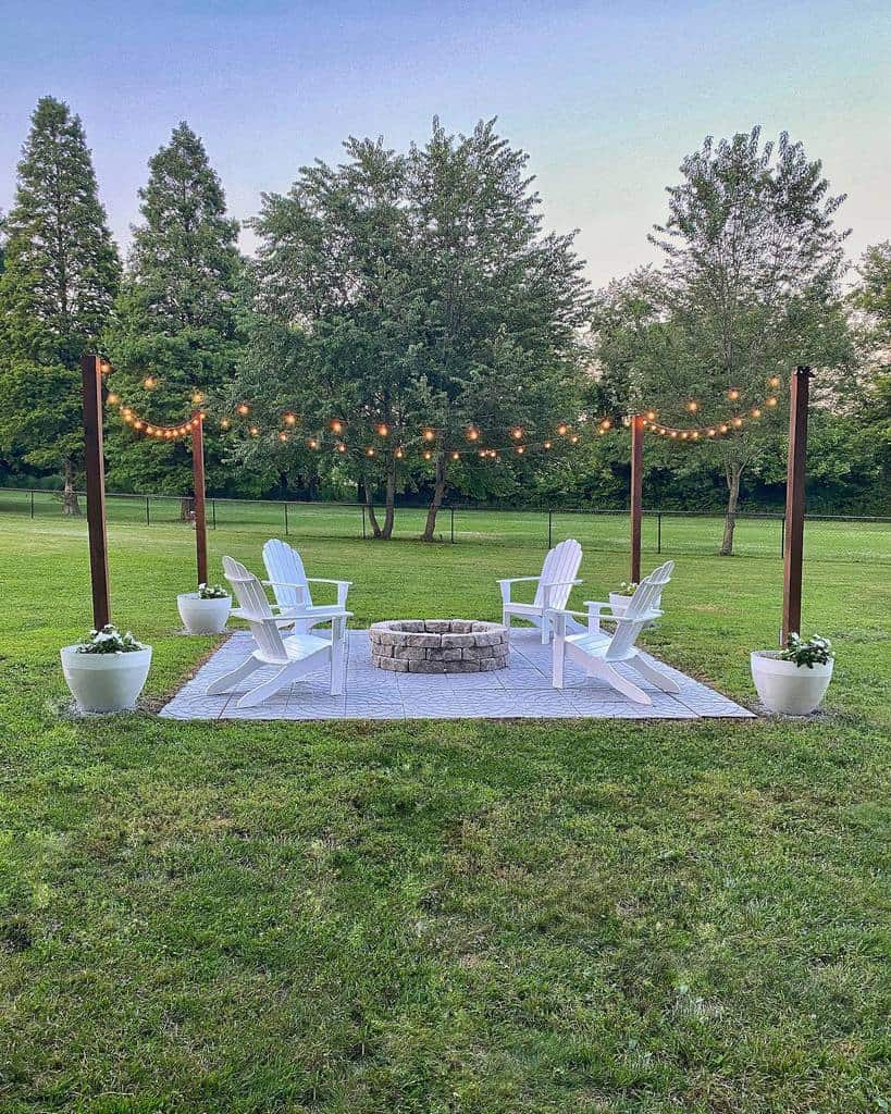 diy stone paver patio with string lighting and white chairs