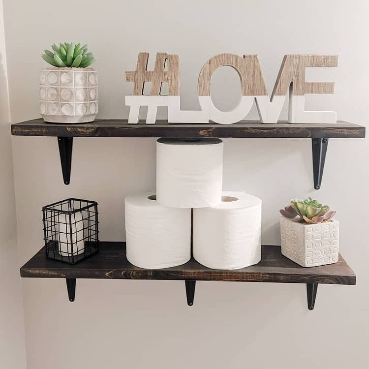 Rustic bathroom shelves with succulents, #LOVE decor, and stacked toilet paper rolls.
