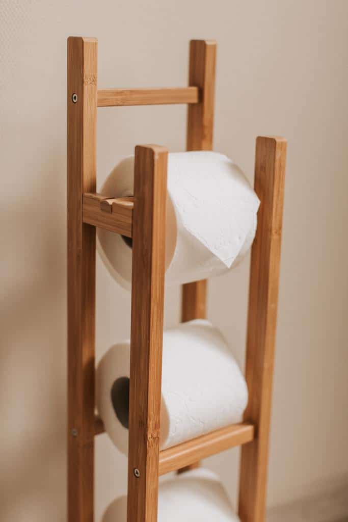 Wooden toilet paper holder with multiple rolls stored vertically.