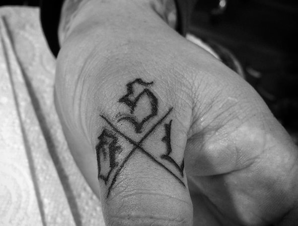 Black and white tattoo of Gothic letters on a finger