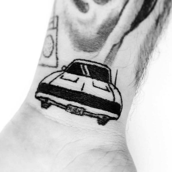 Minimalist black ink Dodge muscle car tattoo on wrist, featuring a bold front view with clean lines for a sleek and classic look.