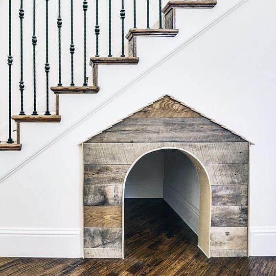 A small wooden dog house built into the space beneath a staircase