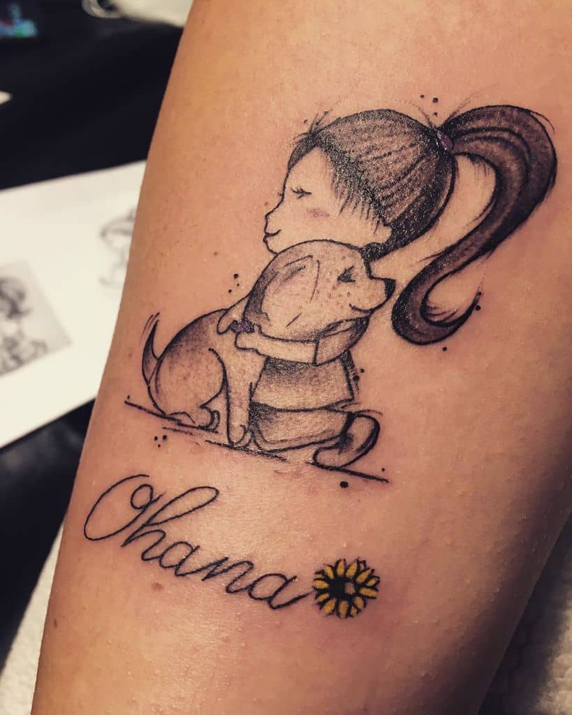 Sketch-style tattoo of a girl hugging a dog with 'Ohana' written below, symbolizing love, family, and companionship.