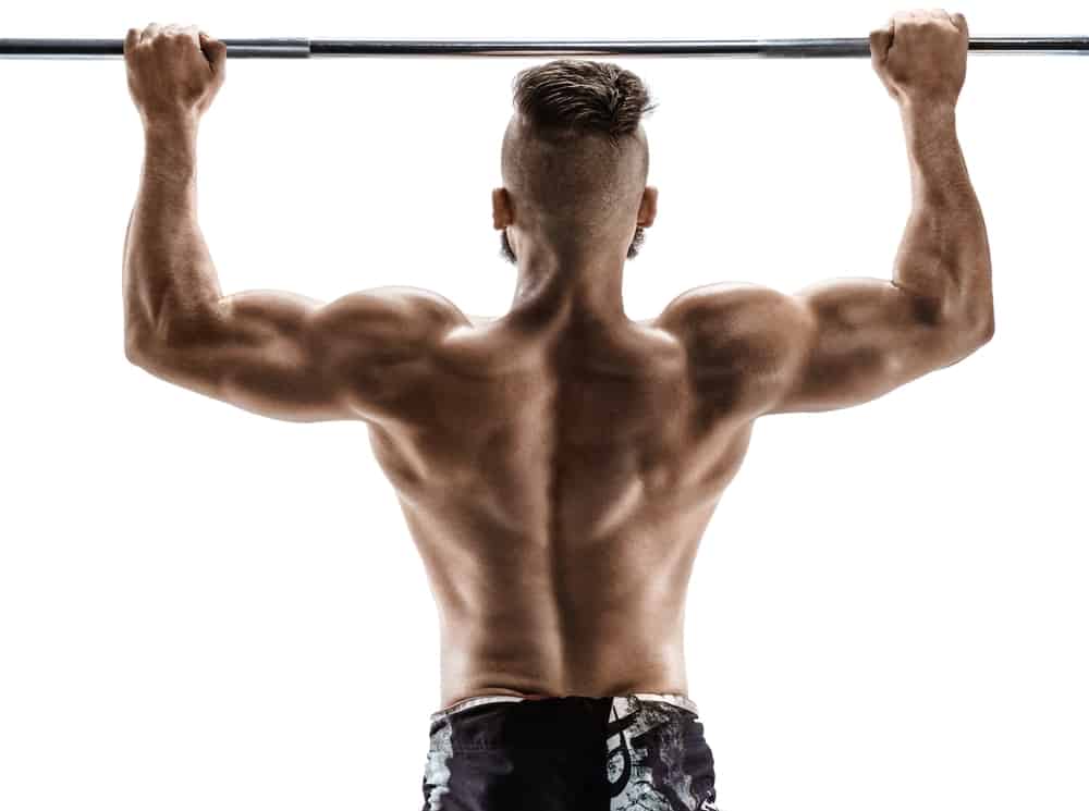 back of young man doing pull ups on white background