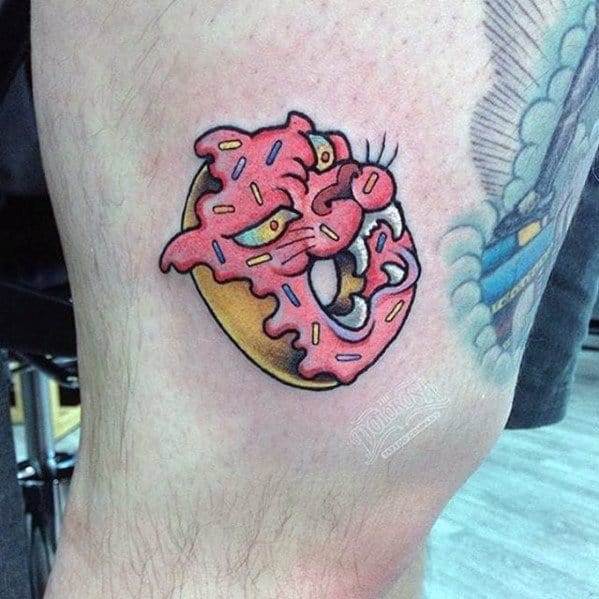 Tattoo of a pink frosted donut with sprinkles, shaped into an angry panther face for a fierce and quirky twist.