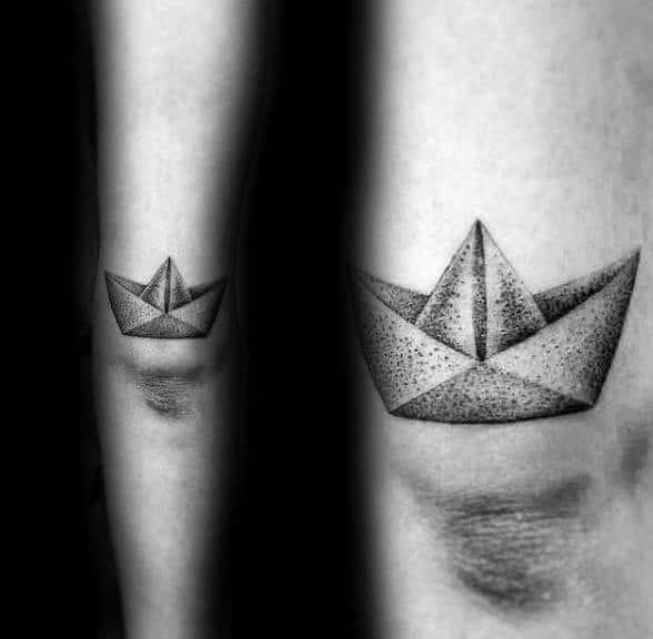 Minimalist paper boat tattoo with dotwork shading, placed on the arm, symbolizing simplicity, nostalgia, and life’s journey.