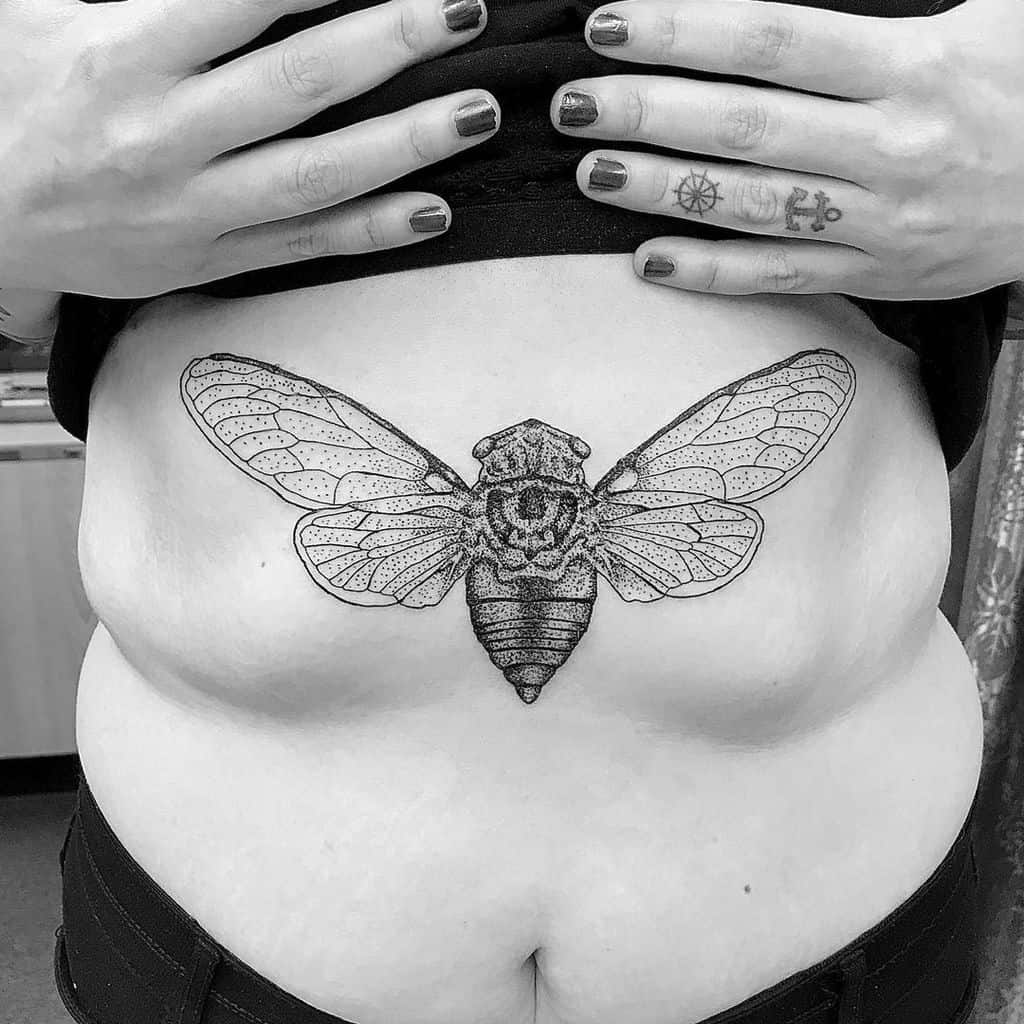 Black and white tattoo of a cicada on a woman's abdomen