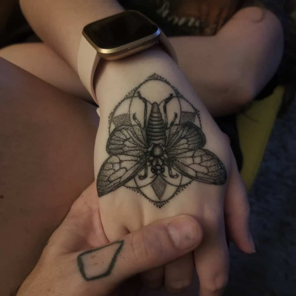 Elegant hand tattoo featuring a cicada in intricate dotwork style, with fine lines and geometric patterns enhancing its artistic appeal