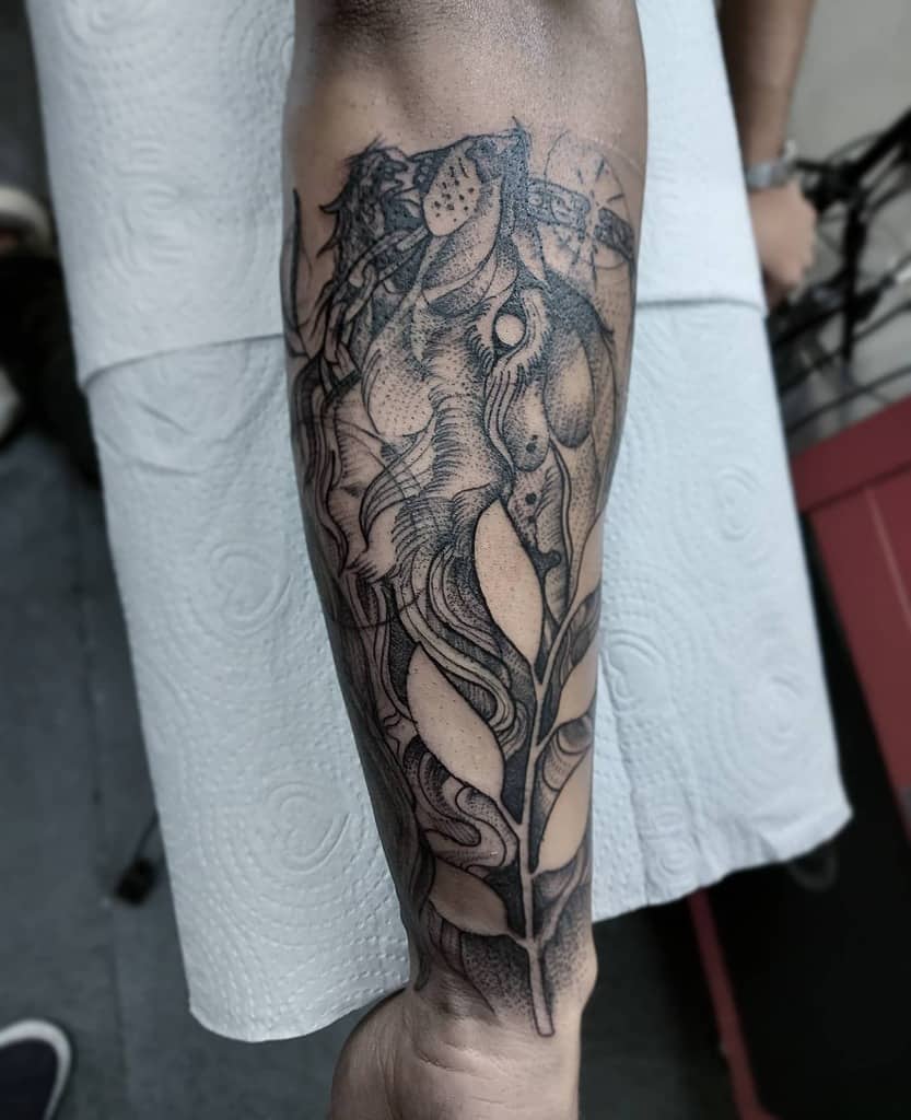 Intricate dotwork tattoo showcasing a Norse wolf intertwined with organic leaf motifs, combining nature and mythology for a unique design