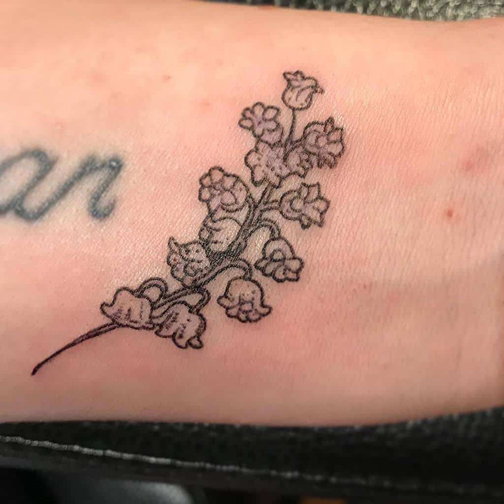 Delicate fine-line Lily of the Valley tattoo, featuring small, detailed bell-shaped flowers with soft shading for a subtle look