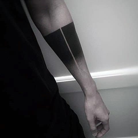 Abstract tattoo design on a person's forearm with dark geometric shading