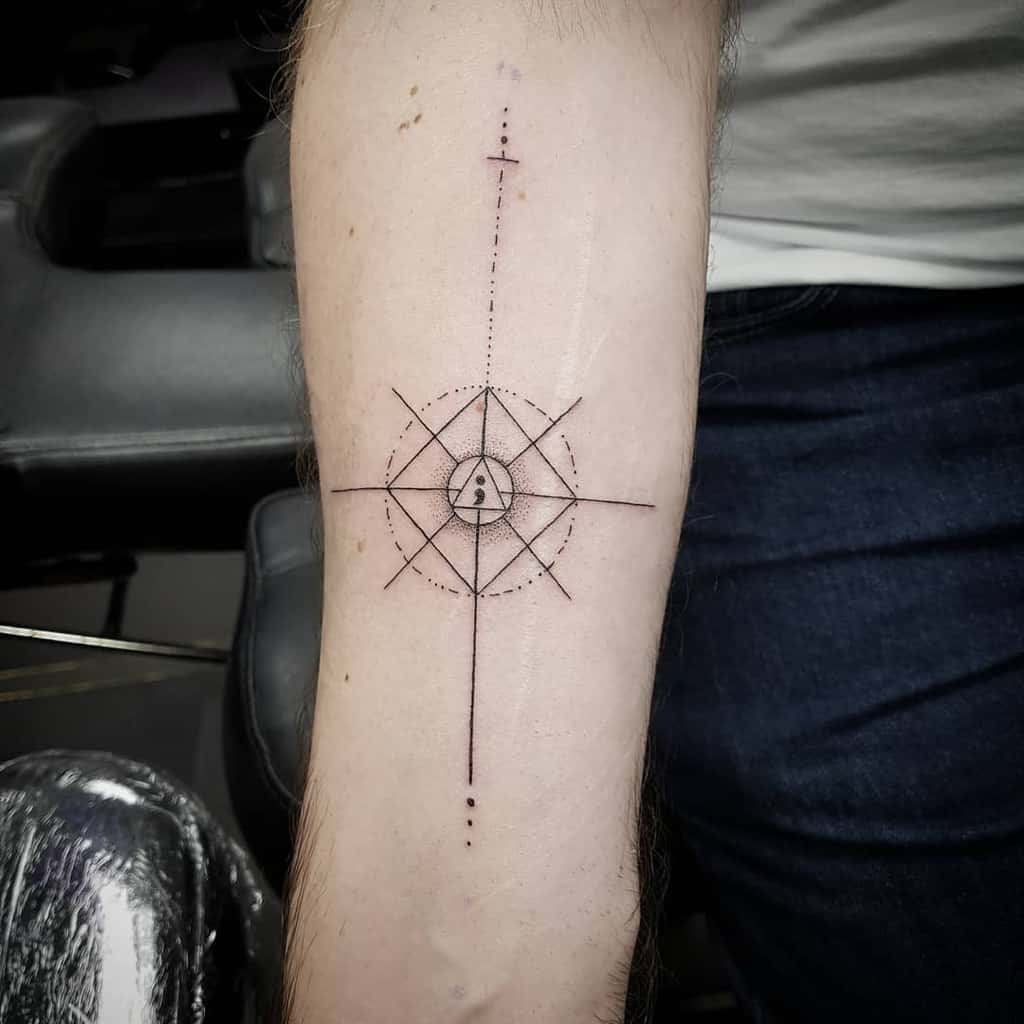The tattoo features a geometric design resembling a compass or web, with a central semicolon incorporated into the pattern. The intricate linework and dot details enhance the precision and balance of the tattoo.