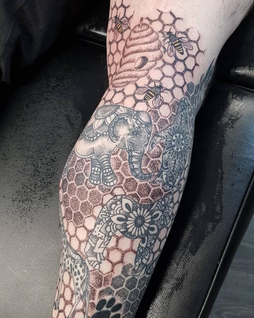 Leg sleeve tattoo featuring an elephant, honeycomb pattern, bees, giraffe and mandala floral designs