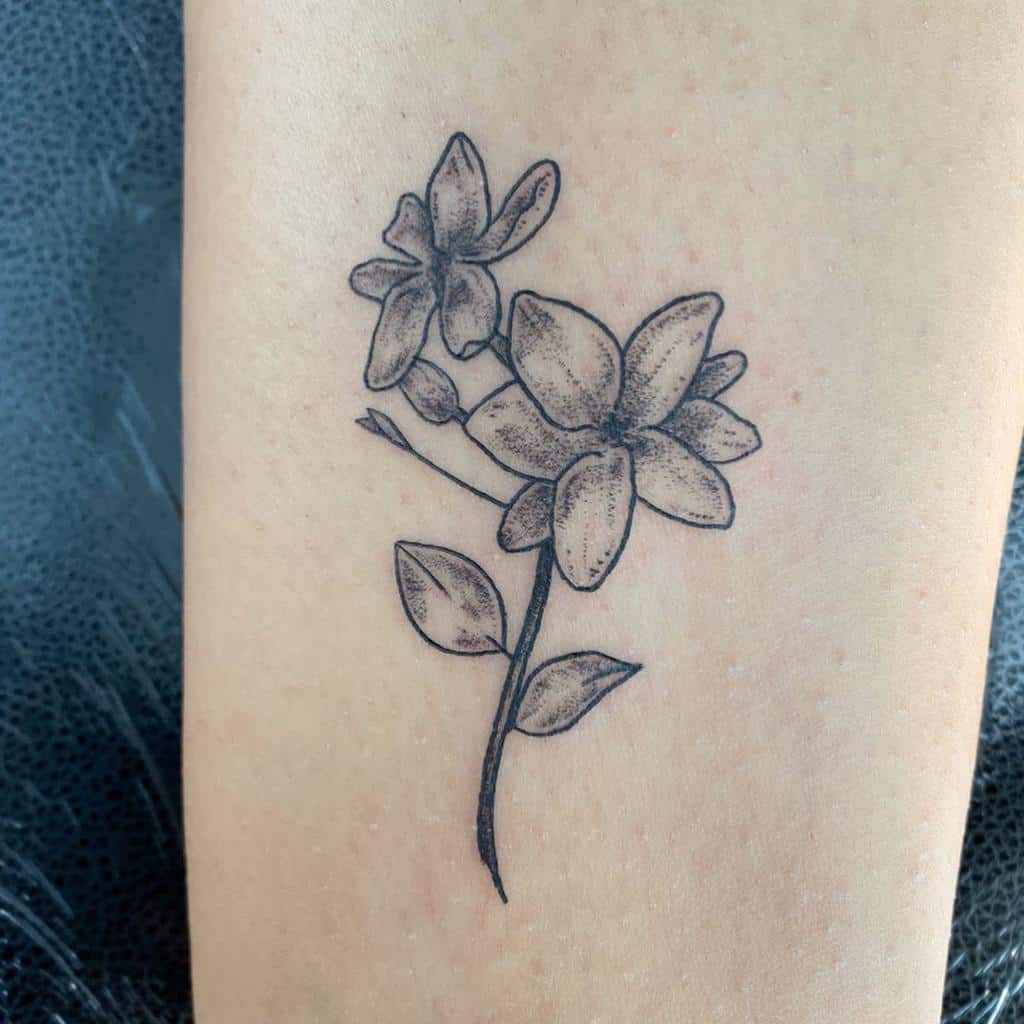 A delicate line tattoo of two jasmine flowers with leaves on skin