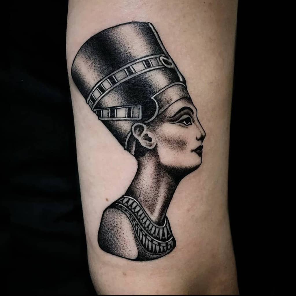 Nefertiti's iconic bust tattooed in black and gray ink graces an arm