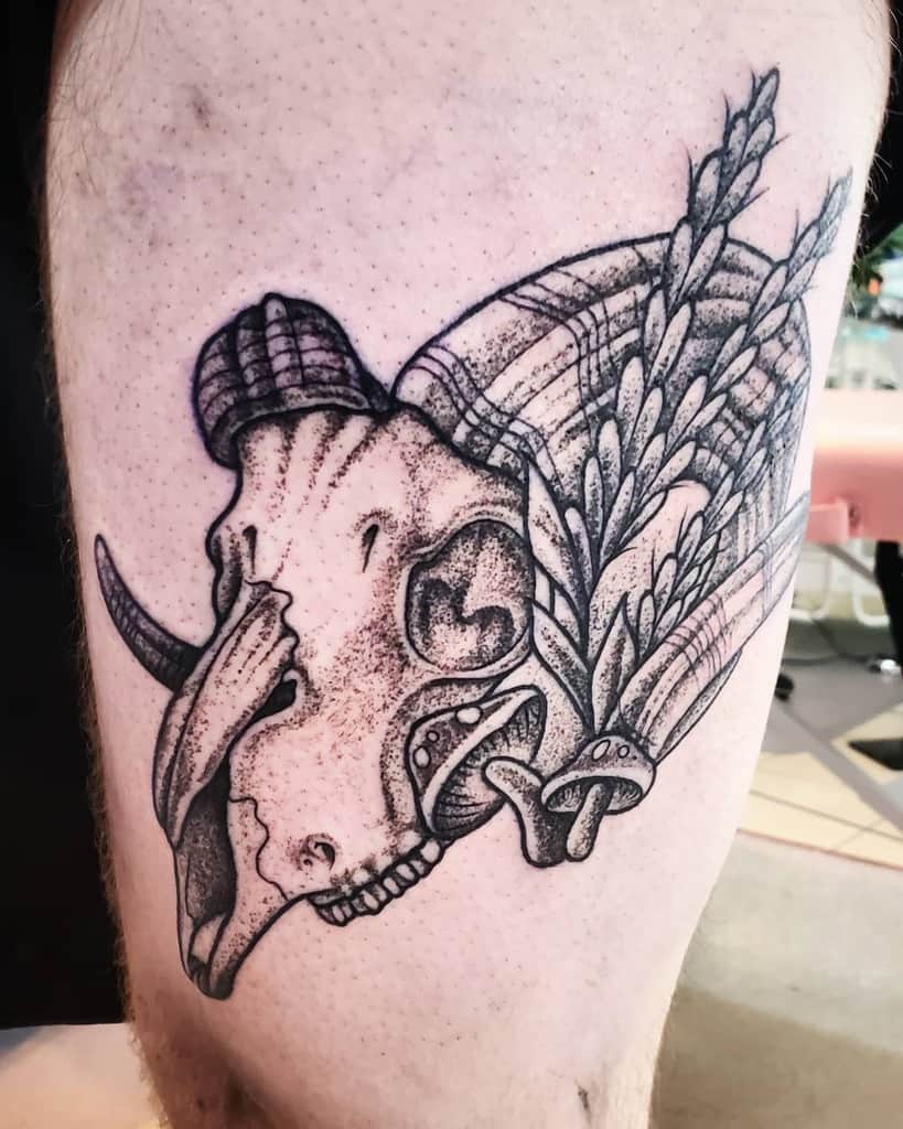 Tattoo of a ram skull and wheat stalks on the upper leg