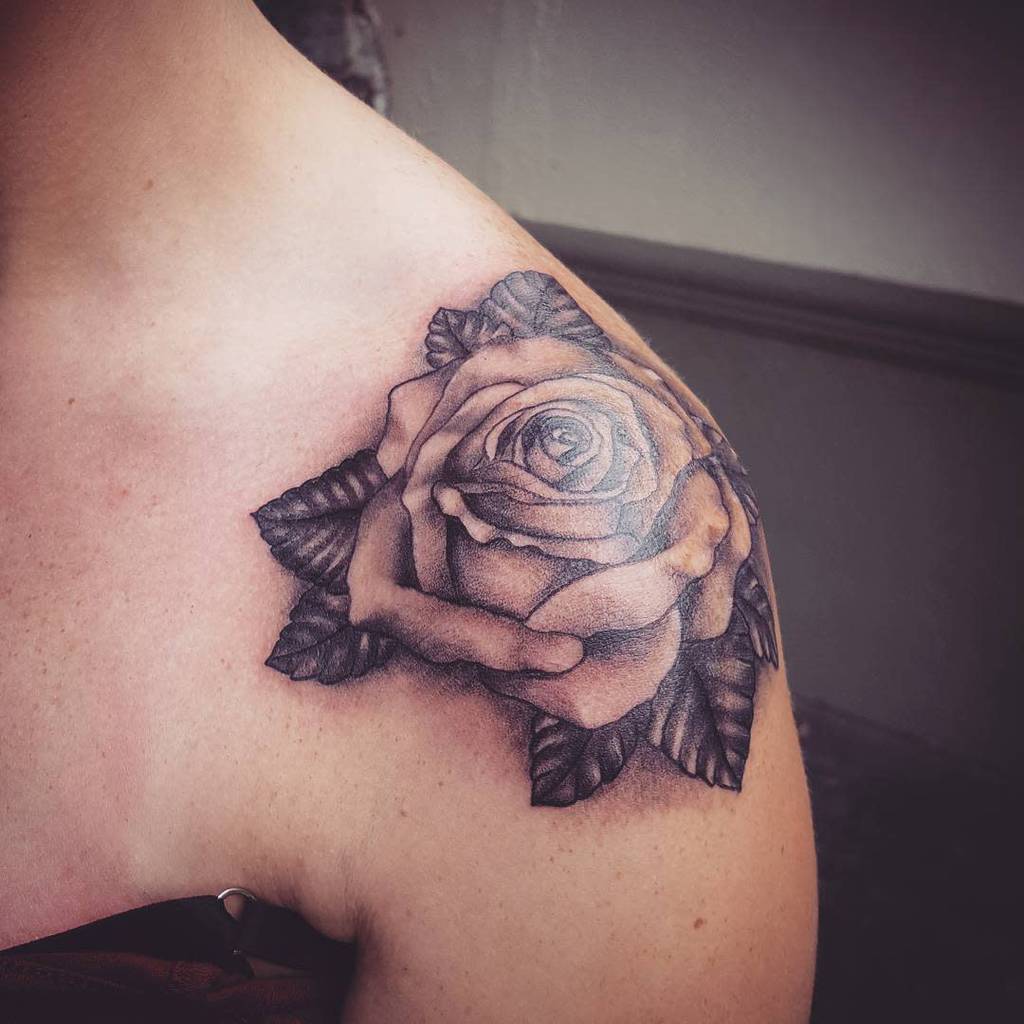 Detailed black and gray rose tattoo on a person's shoulder