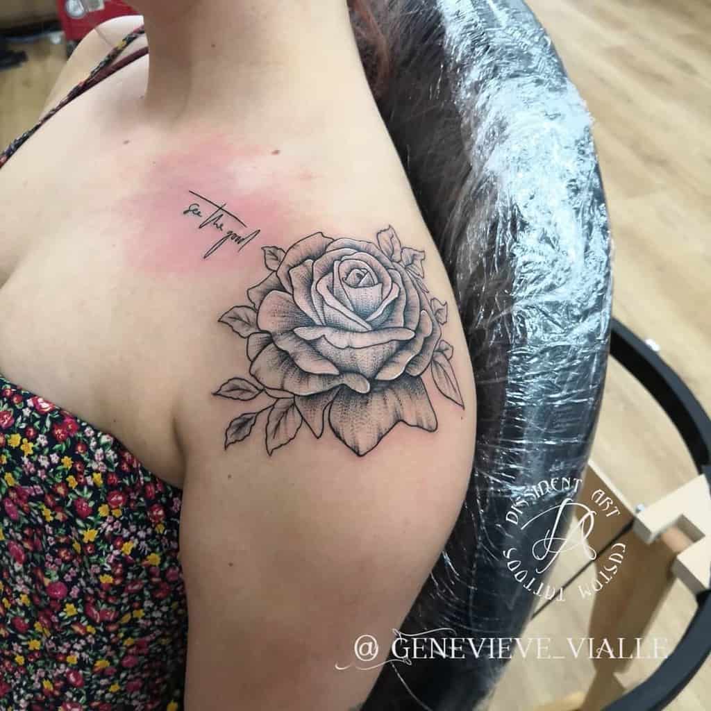 A detailed black and grey rose tattoo on the shoulder, featuring soft shading and a fine line, dotwork style, with a handwritten quote above