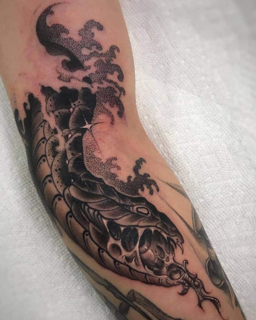 Detailed black ink tattoo of a snake coiled along an arm with dot shading and stylized waves in the background