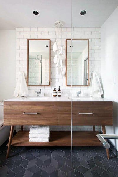 Bathroom with double wood-framed mirrors, wooden vanity, and white subway tile backsplash.