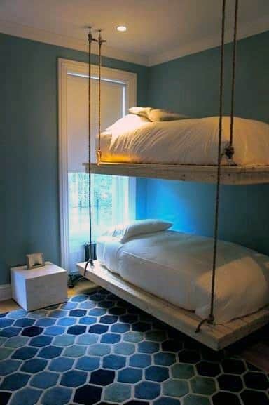 Hanging bunk beds with rope supports, cozy bedding, and a vibrant blue room decor.