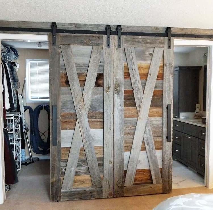 Rustic double sliding barn doors with an X-pattern design leading to a closet and bathroom area.