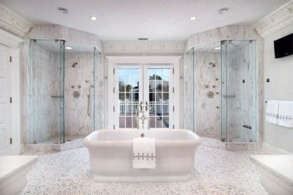 Luxurious white marble bathroom with a central freestanding tub, dual glass showers, and a large shower window