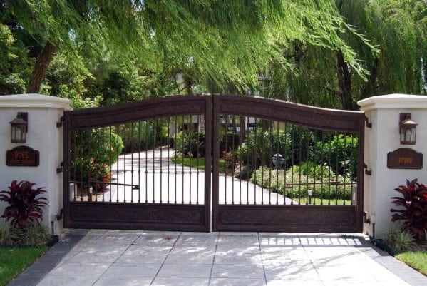 Wooden double driveway gate with arched top and vertical metal bars.