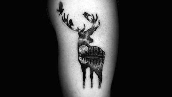 Black and grey tattoo of a deer silhouette filled with a night forest scene, birds on the antlers, and a glowing moon in the background.