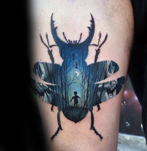Tattoo of a beetle silhouette containing a dark forest scene with a child, moonlight, and eerie eyes hidden in the trees.