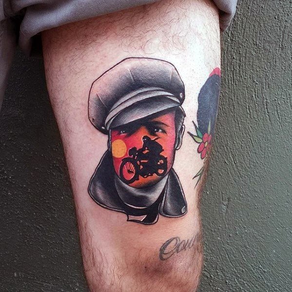 Bold tattoo of a man in a cap with a sunset motorcycle scene creatively blended into his face, merging classic portrait and biker themes.