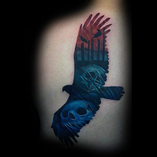 Dark and vibrant tattoo of a flying hawk with skulls, trees, and eerie faces blended into its wings, symbolizing death and mystery.