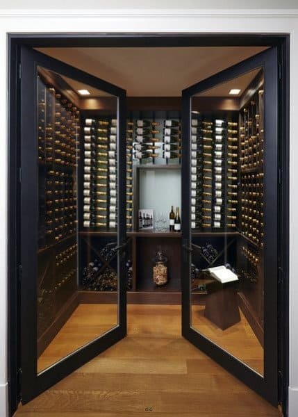 Modern wine cellar with glass doors, numerous wine bottles on display, and a stylish wooden floor for a true wine lover