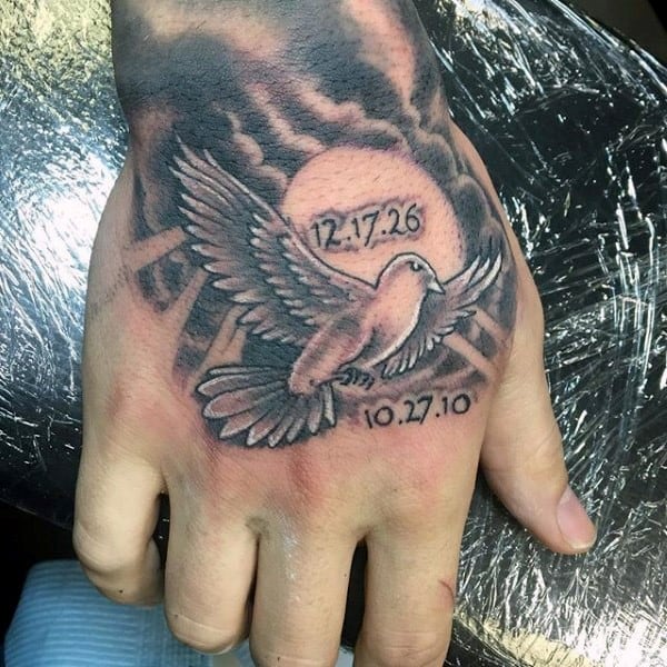 Hand tattoo of a dove with wings spread, dates "12.17.26" and "10.27.10" near the sun
