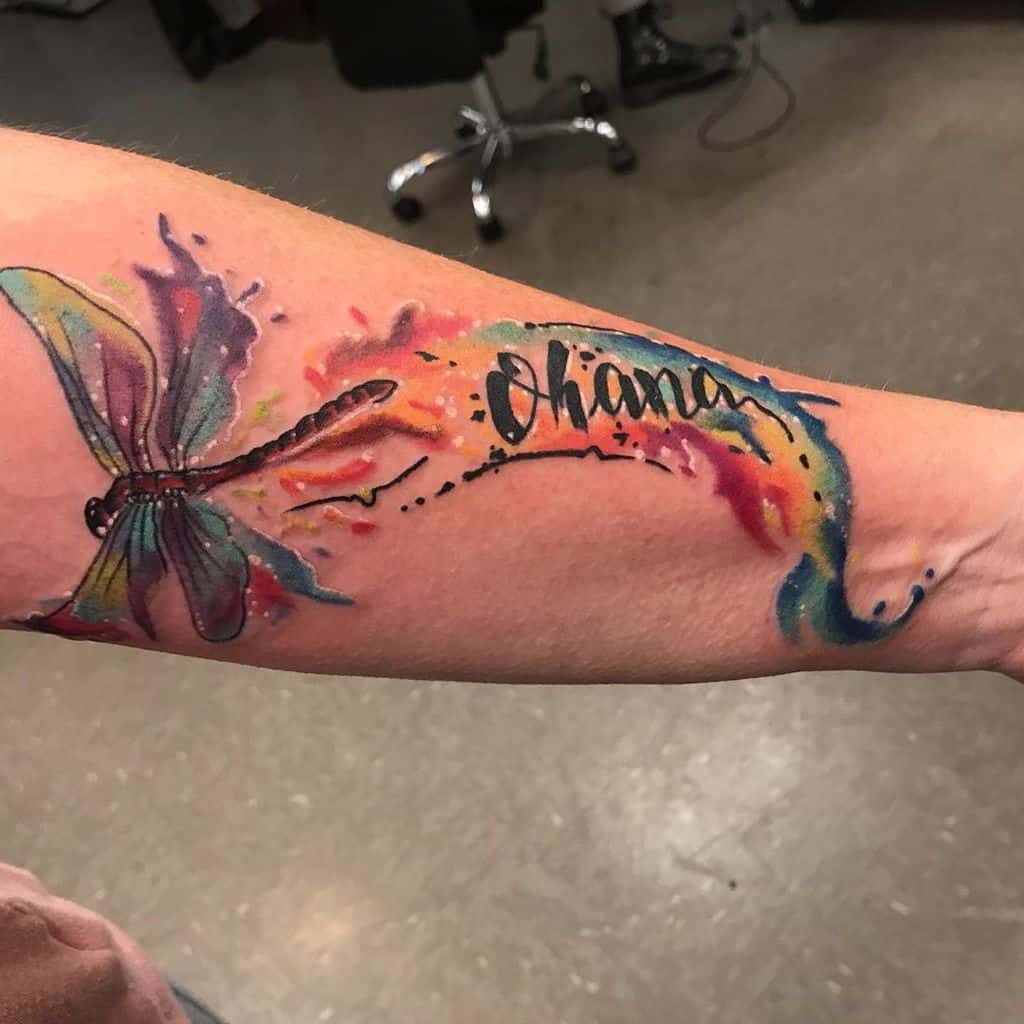 Vibrant watercolor tattoo of a dragonfly with 'Ohana,' symbolizing family, transformation, and the beauty of life.
