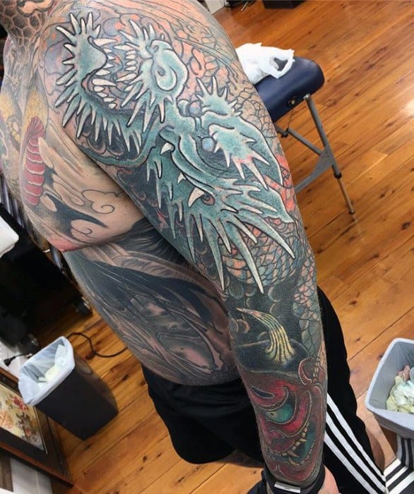 Blast-over arm tattoo with a dragon, featuring bold colors and intricate details