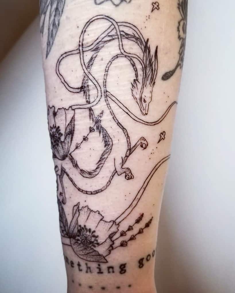 A black and white tattoo of a dragon intertwined with flowers, located on the forearm. The design includes delicate lines and abstract elements.