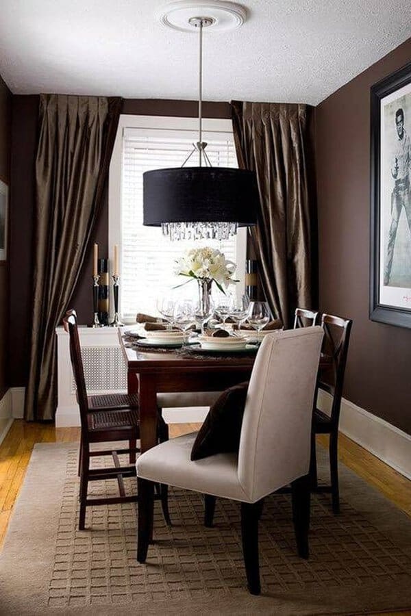 Sophisticated dining room with dark brown curtains, a black chandelier, and a stylish table setting.