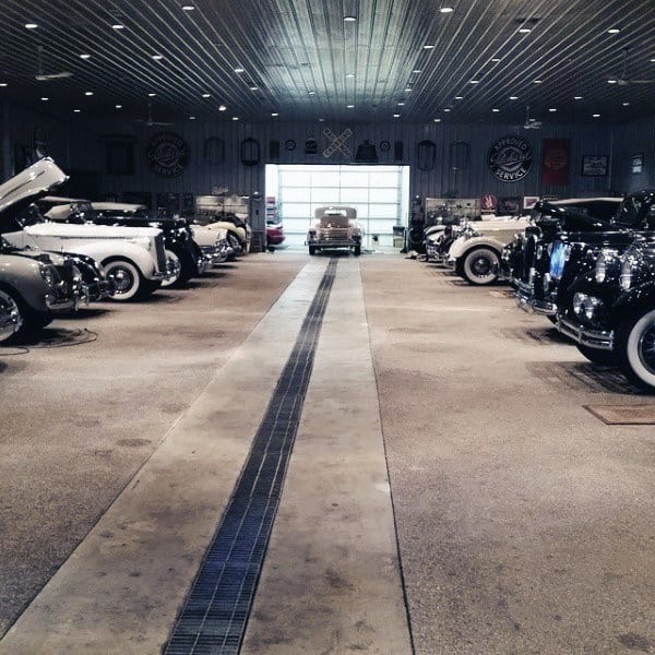 A vintage car showroom with polished floors and a ribbed metal ceiling with built-in lights.