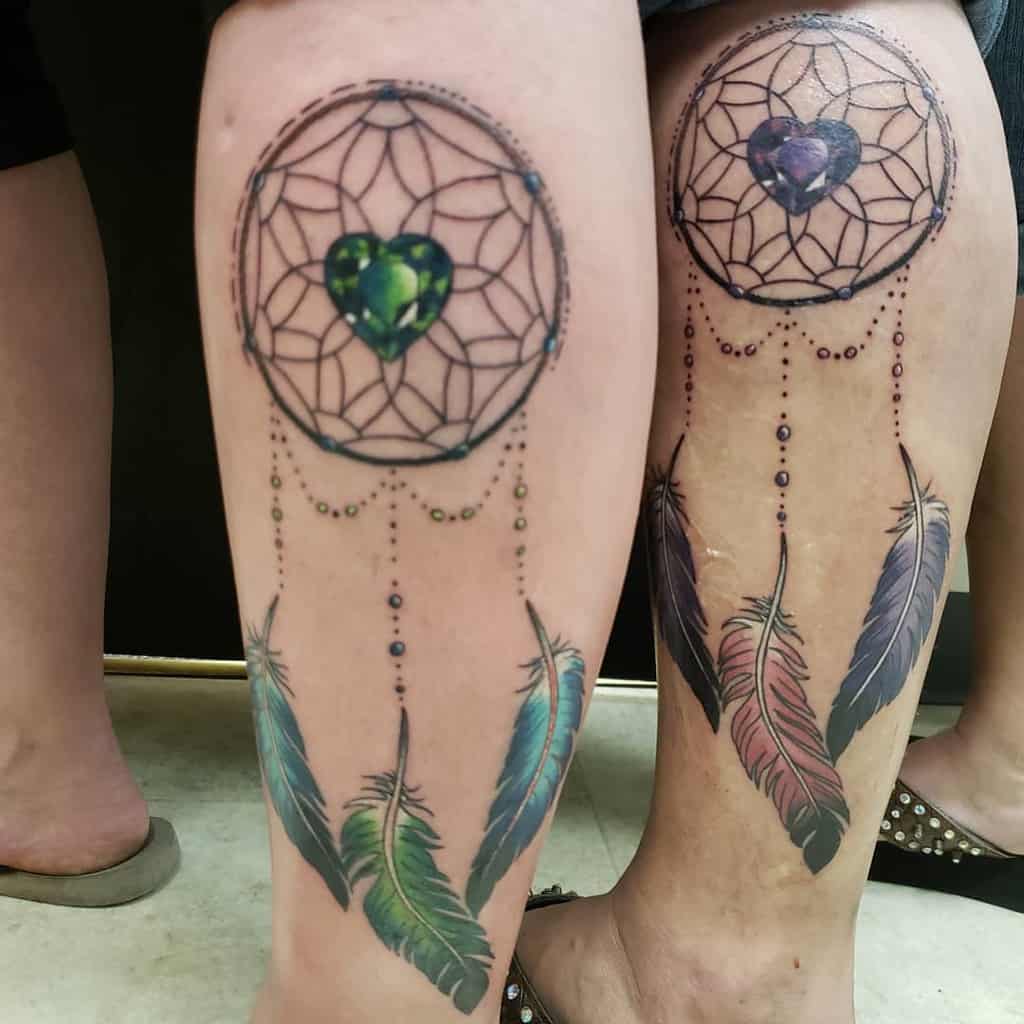 Matching mother-daughter dreamcatcher tattoos with heart-shaped gems and colorful feathers