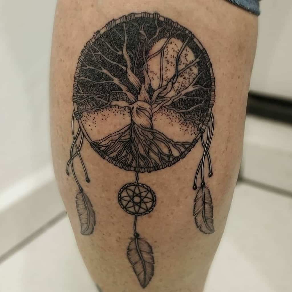 The tattoo features Yggdrasil within a dreamcatcher, blending Norse mythology with Native American symbolism for a unique spiritual design.